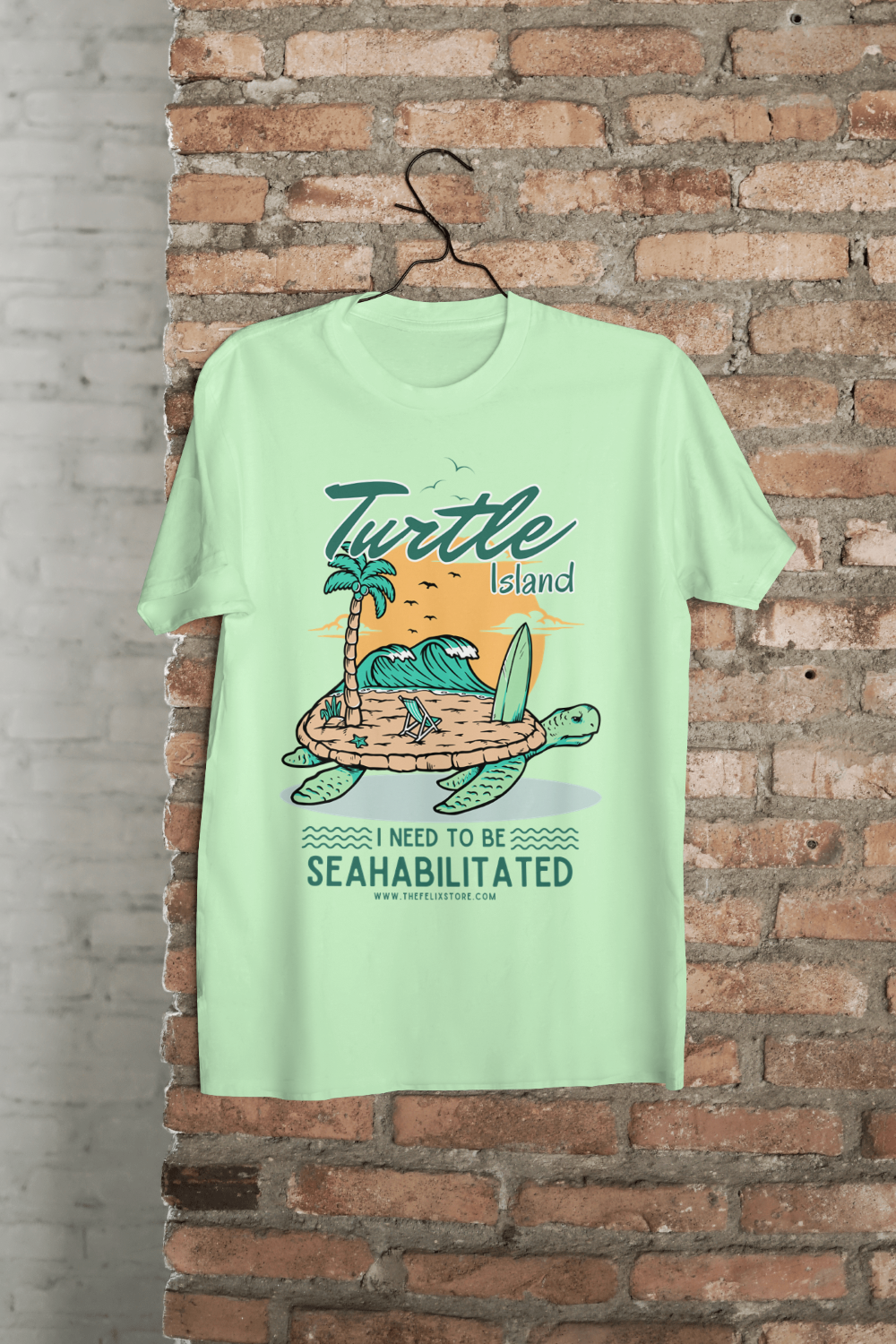 t-shirt featuring a colorful turtle carrying a tropical island with the phrase “I Need to Be Seahabilitated” 