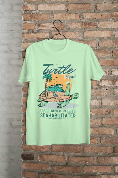 t-shirt featuring a colorful turtle carrying a tropical island with the phrase “I Need to Be Seahabilitated” 